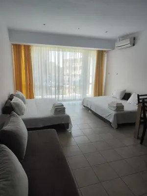 a hotel room with two beds and a large window at Umi Apartments in Sunny Beach