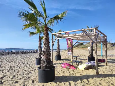 a person laying on the beach next to a tent and palm trees at Umi Apartments in Sunny Beach