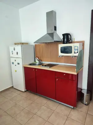 a kitchen with a white refrigerator and red cabinets at Umi Apartments in Sunny Beach