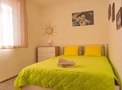 a bedroom with a green bed with yellow pillows at Cozy 1-bedroom apartment 5 min from the beach in Varna City