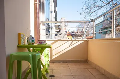 a balcony with a green table and stool and a window at Cozy 1-bedroom apartment 5 min from the beach in Varna City