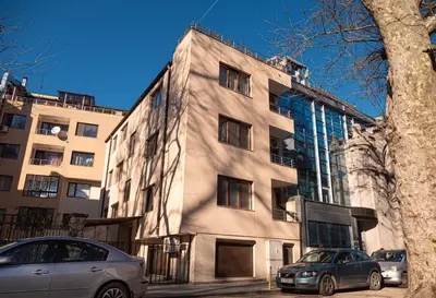 a building with two cars parked in front of it at Cozy 1-bedroom apartment 5 min from the beach in Varna City