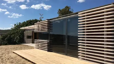 a modern house with glass windows on a wooden deck at Firstline Beach Camp in Sozopol