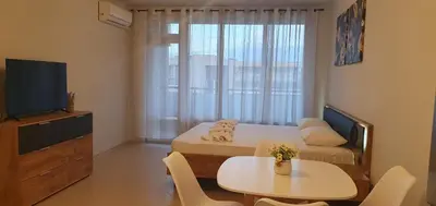 a small room with a bed and a table and a television at Central Beach Ravda Apartments in Ravda