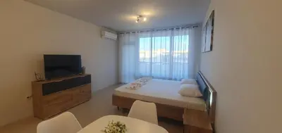 a small room with a bed and a television and chairs at Central Beach Ravda Apartments in Ravda
