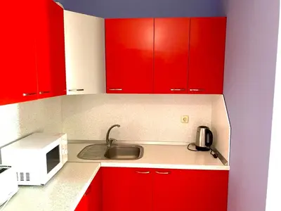 a kitchen with red cabinets and a sink and a microwave at DELFIN Penthouse amazing view in Sveti Vlas