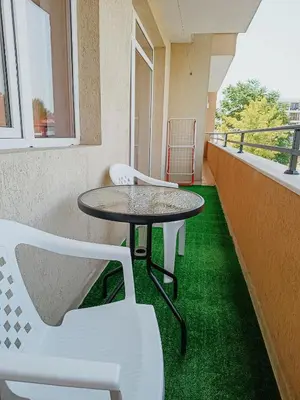 a table and chairs on a balcony with green grass at Kamelia Garden Apartment in Sunny Beach