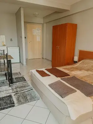a bedroom with a large bed and a refrigerator at Kamelia Garden Apartment in Sunny Beach