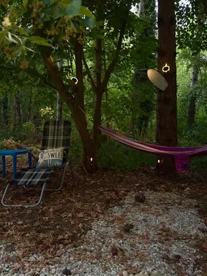 a hammock and a chair in the woods at Каравана Синята Маймуна плаж Градина # RV Blue Monkey on the beach in Chernomorets