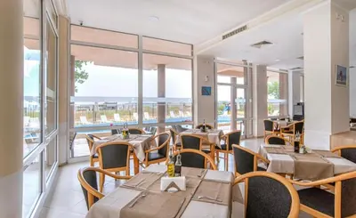 a restaurant with tables and chairs and windows at Студио 310 на първа линия in Chernomorets