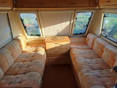 a living room in an rv with a couch and two windows at Къмпинг Европа Юг in Burgas City