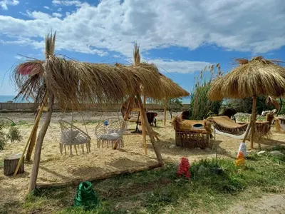 a hut with chairs and umbrellas on the beach at Къмпинг Европа Юг in Burgas City