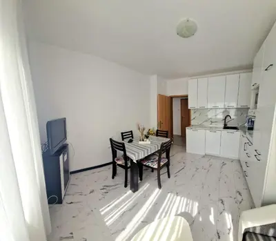 a living room with a table and a kitchen at Апартамент Бижу М in Pomorie