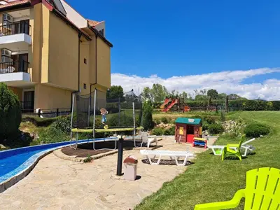 a backyard with a pool and a playground next to a building at Lidda Relax in Oasis Beach Kamchia in Bliznatsi