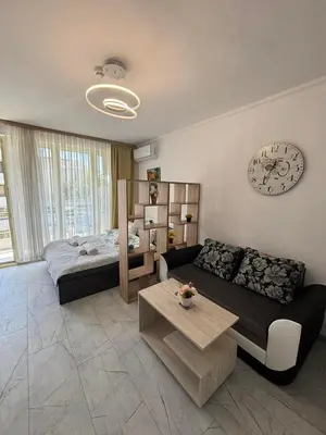 a living room with a couch and a bed at Прекрасно студио in Sunny Beach