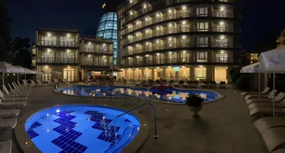 a person walking in front of a building at night at Прекрасно студио in Sunny Beach