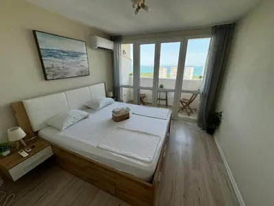 a bedroom with a bed and a large window at Апартамент Панорама Лазур in Burgas City