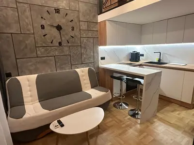 a living room with a couch and a clock on the wall at Studio Lazur in Burgas City