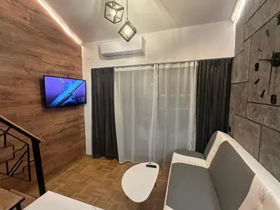 a living room with a couch and a tv on a wall at Studio Lazur in Burgas City