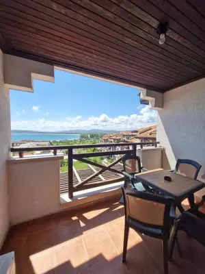 a balcony with a table and chairs and a view of the ocean at Апартамент Къмпинг Градина in Chernomorets