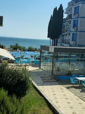 a pool with tables and chairs and a building at POMORIE Luxury Appartment in Pomorie