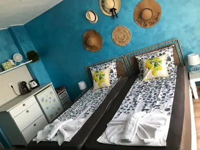 a bedroom with two beds and a blue wall at Студио - Морско бягство in Primorsko