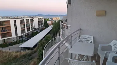 a balcony with white chairs and tables on a building at Holidays Apartment Atlantis Sarafovo in Burgas City
