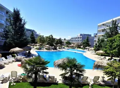 a large swimming pool with chairs and palm trees at Holidays Apartment Atlantis Sarafovo in Burgas City