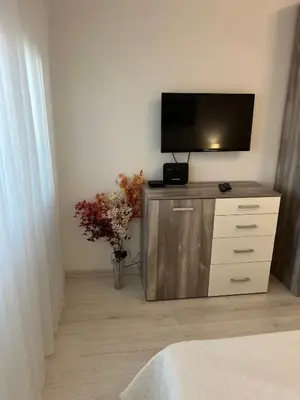 a television on a cabinet with a vase of flowers at Tei-Zi apartments2 in Burgas City