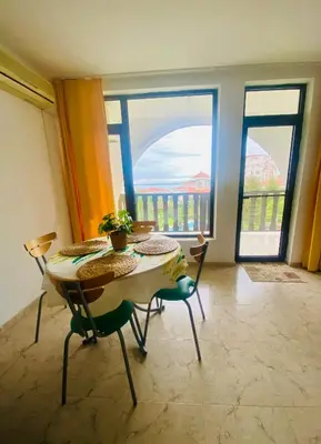 a table and chairs in a room with large windows at Cozy apartment in Kambani 1 in Sveti Vlas