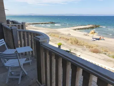a balcony with a table and a chair and a beach at Solar Rise apartment in Pomorie
