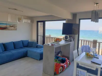 a living room with a blue couch and a television at Solar Rise apartment in Pomorie