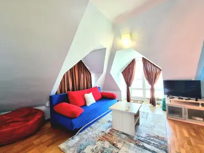 a living room with a blue couch and red pillows at Two-Floor Sunny Apartment in City Centre in Burgas City