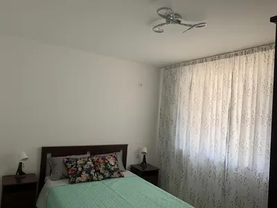 a bedroom with a bed with a green blanket and a window at Sunny holidays in Byala