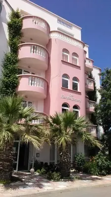 a pink building with palm trees in front of it at Guest House Malkata Stopanka in Primorsko