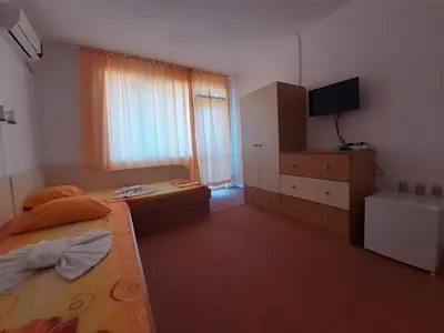 a bedroom with a bed and a dresser and a television at Guest House Malkata Stopanka in Primorsko