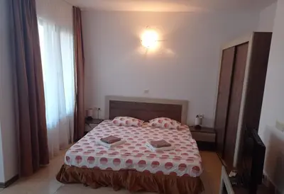 a bedroom with a bed with a red and white comforter at Студио Море in Chernomorets