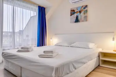 a white bedroom with a large bed with towels on it at AT apartment - Sea View in Varna City