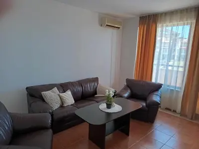 a living room with a leather couch and a table at Апартамент Плаж Червенка in Chernomorets