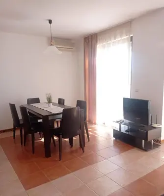 a dining room with a table and chairs and a television at Апартамент Плаж Червенка in Chernomorets