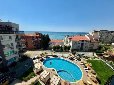 a view of a swimming pool with chairs and the ocean at Апартамент СВЕТИ ВЛАС 1 in Sveti Vlas