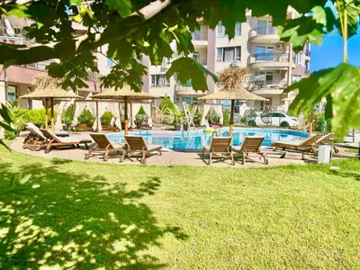 a group of chairs and umbrellas next to a swimming pool at Апартамент СВЕТИ ВЛАС 1 in Sveti Vlas