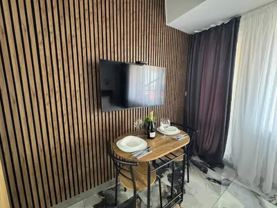 a wooden table with plates on it in a room with a television at Студио СВЕТИ ВЛАС 2 in Sveti Vlas