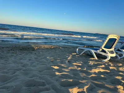 a beach chair sitting on the sand on the beach at Kalia A5 Sunny Beach in Sunny Beach