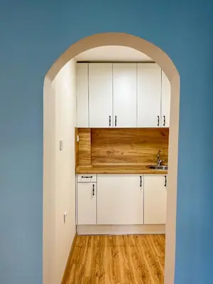 an archway leads into a kitchen with white cabinets at Cosy Home in Burgas City