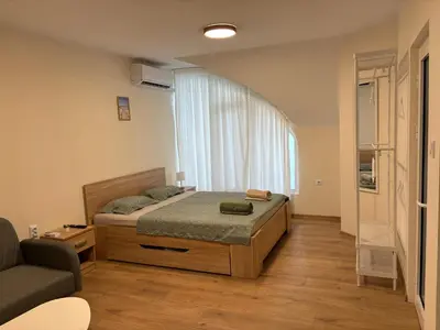 a bedroom with a bed and a couch and a window at Студио за гости При Нана in Burgas City