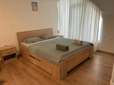 a bedroom with a wooden bed with two bags on it at Студио за гости При Нана in Burgas City