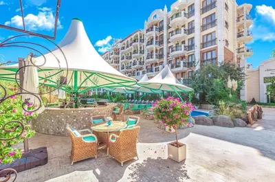 a patio with chairs and a table and a building at HARMONY SUITES Grand Resort PREMIUM Ferienwohnung in Sunny Beach