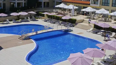 a swimming pool with umbrellas and chairs and a hotel at Апартаменти Бяла Бийч - Apartments Byala Beach in Byala