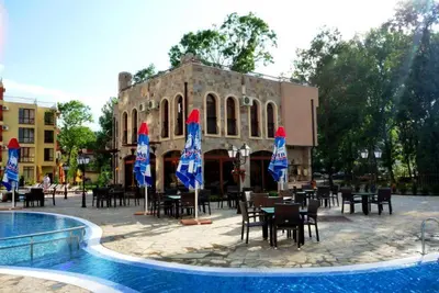 a restaurant with tables and chairs and umbrellas in front of a building at Kalia Sunny Beach 1 bedroom apartment in Sunny Beach